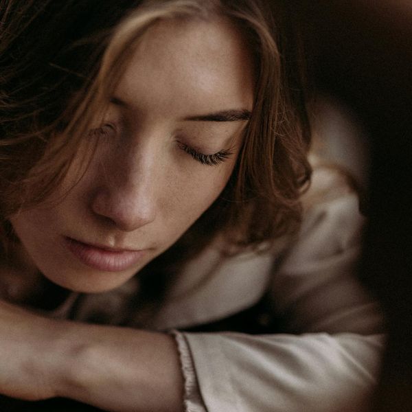 Person meditating in a calm environment, with soft cyan light creating a tranquil atmosphere.